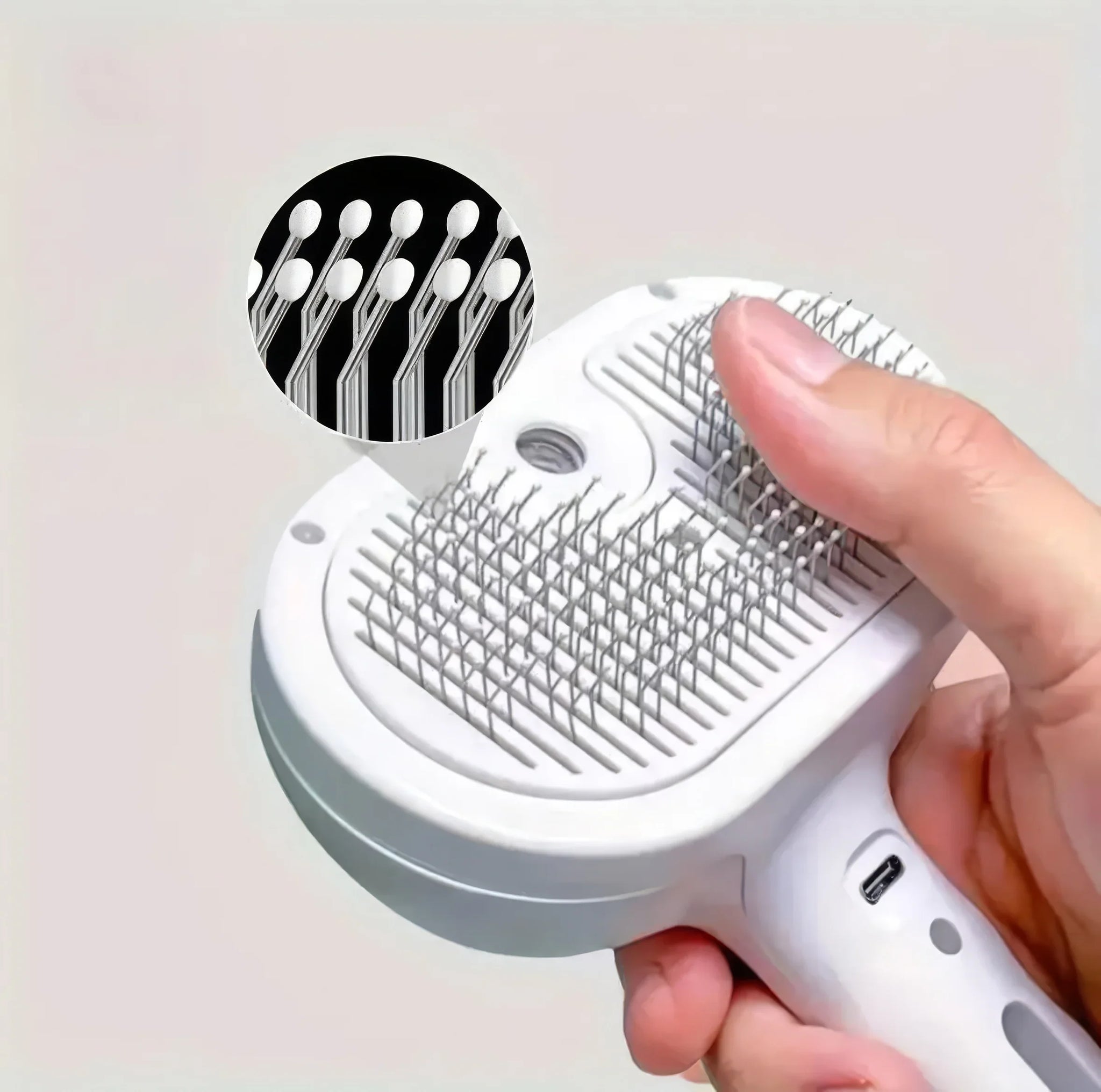 Close-up of pet grooming brush with metal bristles and protective ball tips, held in hand